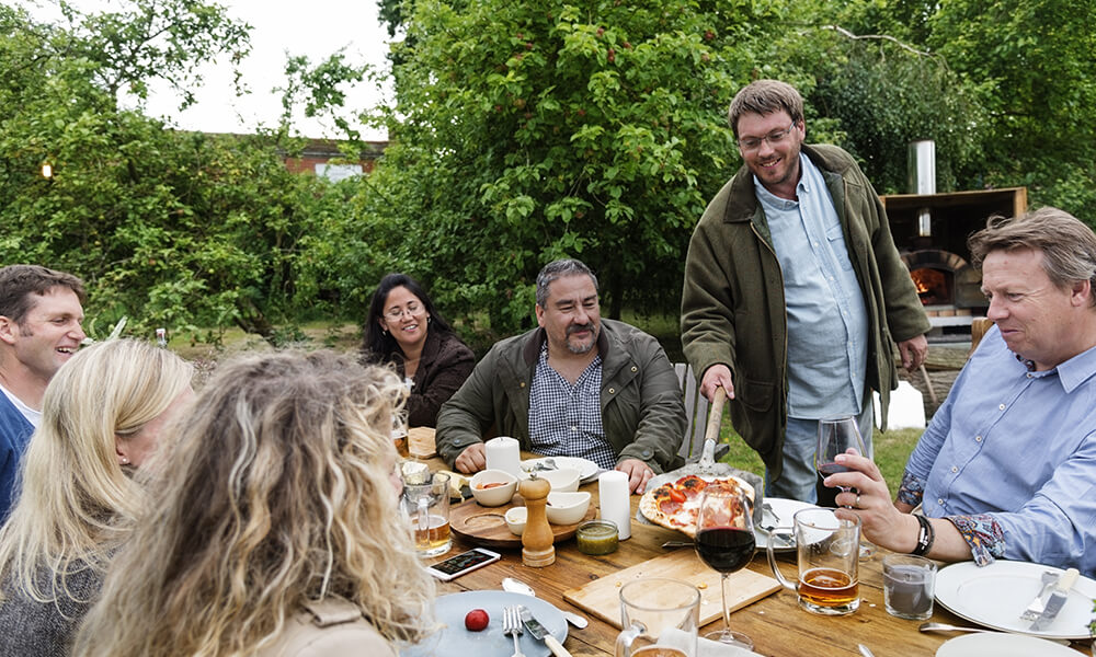 group of adults eating pizza at a farm