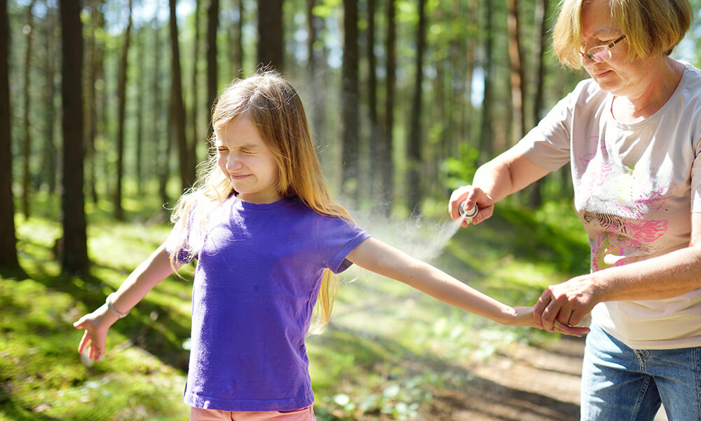 a woman spraying her child to protect against ticks